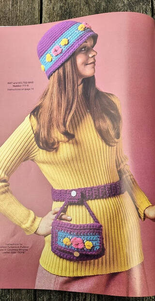 Columbia Minerva 777-5 Hat and Belted bag in purple with a turquoise stripe and pink and yellow flowers.  Worn by a woman with long hair and a yellow turtle neck ribbed sweater