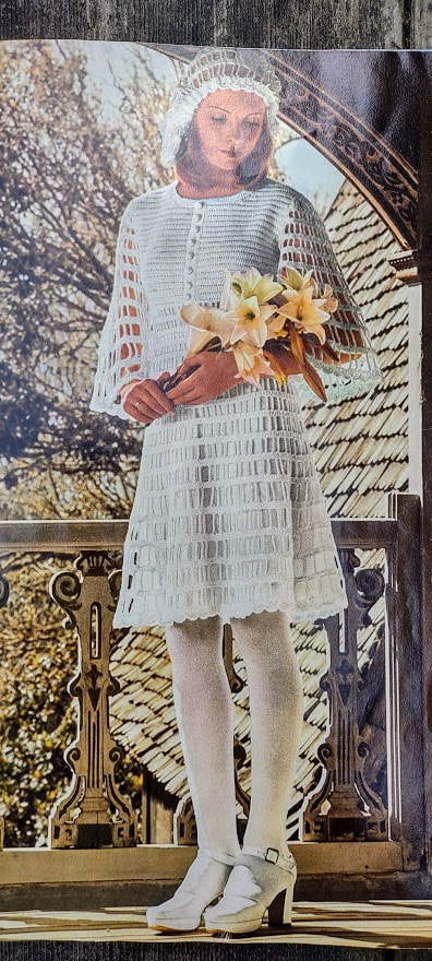 Woman wearing a white knee length dress with a crocheted hat and chunky white heels. Holding yellow/pink lillies